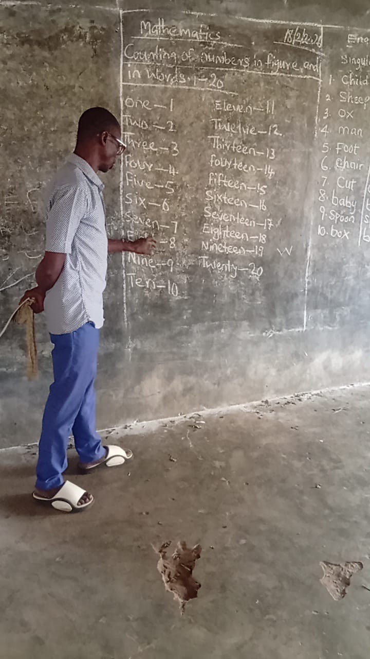 A teacher writing counting numbers on a concrete classroom wall
